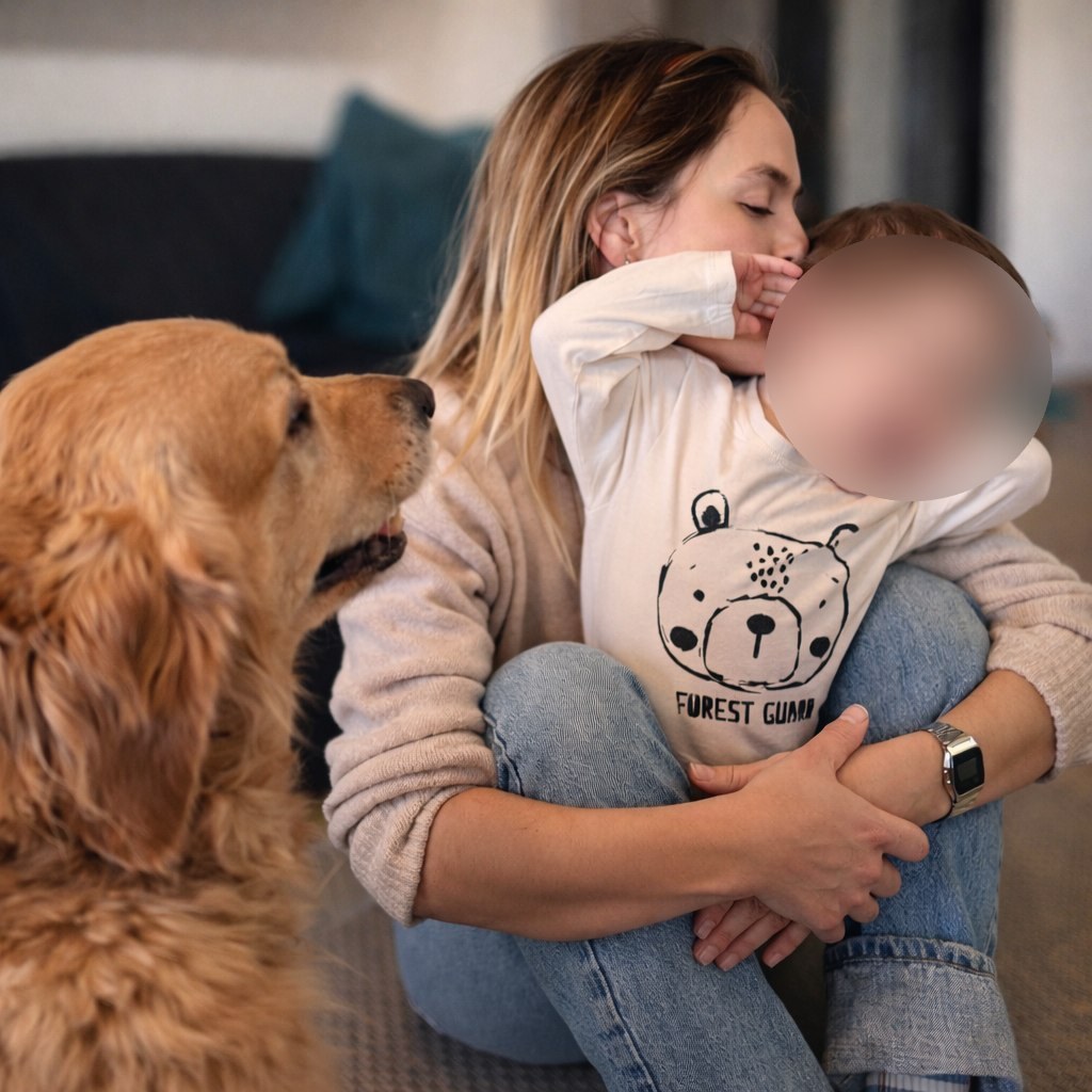 Maman embrassant son bébé, leur golden retriever tout proche