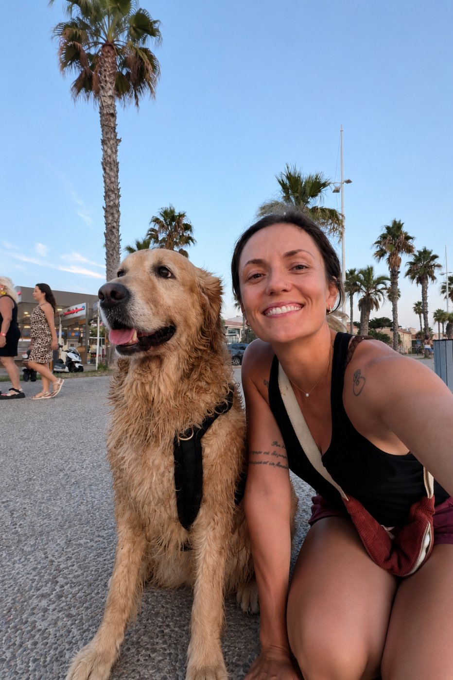Camila souriante avec un golden retriever au bord de mer